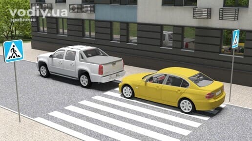 Дорожні знаки 5.38.1, 5.38.2 «Пішохідний перехід», білий пікап та жовтий седан зупинилися біля розмітки 1.14.1 «зебра» на дорозі вздовж будівлі.