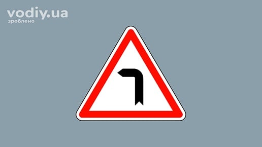 Дорожній знак 1.2 «Небезпечний поворот ліворуч» на сірому фоні. Попередження про заокруглення дороги з обмеженою оглядовістю.