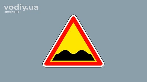 Дорожній знак 1.10 «Нерівна дорога» на жовтому фоні, попередження про хвилястості та напливи на проїзній частині.