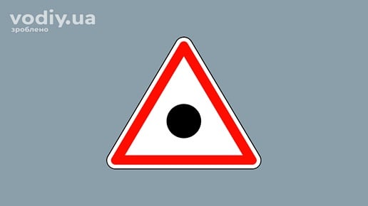 Дорожній знак 1.41 «Місце (ділянка) концентрації дорожньо-транспортних пригод» на сірому фоні.