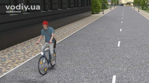 Велосипедист у шоломі рухається по дорозі біля краю проїзної частини, регулювання руху на дорогах міста.