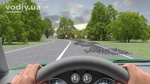 Гравій на асфальті перед крутим поворотом, дорожні знаки 1.4.1 «Напрямок повороту», руки водія на кермі автомобіля.