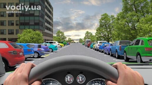 Вид з місця водія на дорогу з припаркованими автомобілями з обох боків, обмежена оглядовість через транспортні засоби вздовж краю проїзної частини.