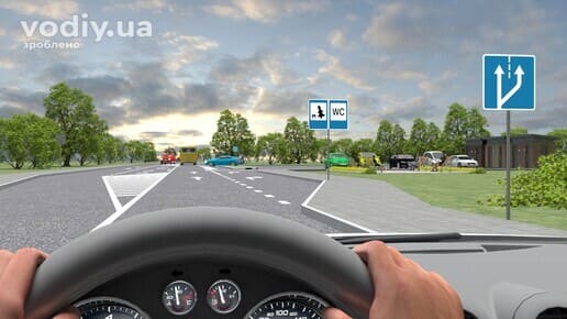 Дорожні знаки: 6.15 «Місце відпочинку», 6.11 «Туалет», 5.20.1 «Початок додаткової смуги руху». Вид з місця водія на зону відпочинку біля дороги.