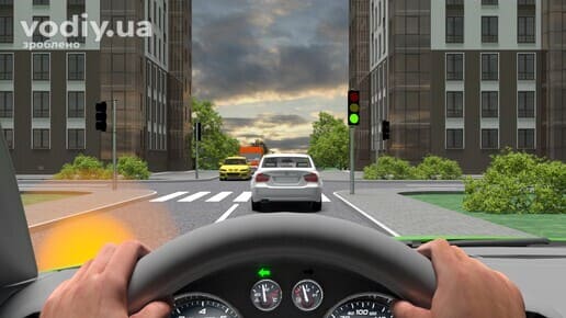 Білий автомобіль перед регульованим перехрестям, зелений сигнал світлофора, пішохідний перехід та зустрічний жовтий автомобіль.