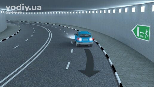 Синій автомобіль з увімкненими ліхтарями заднього ходу в тунелі, дорожній знак 5.80.1 «Покажчики напрямків і відстані до аварійних виходів».
