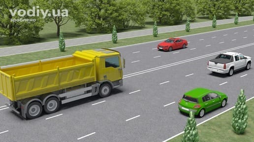 Жовта вантажівка, білий пікап та зелений легковий автомобіль на дорозі з трьома смугами руху в одному напрямку.