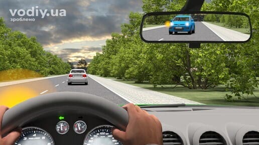 Виконання обгону, синій автомобіль у дзеркалі заднього виду розпочав маневр обгону