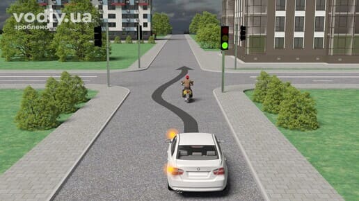 Обгін мопеда білим автомобілем на регульованому перехресті, зелений сигнал світлофора.