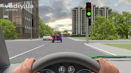 Зелений автомобіль перед перехрестям, зелений сигнал світлофора, мотоцикл з коляскою попереду вмикає лівий поворот, випередження на перехресті.
