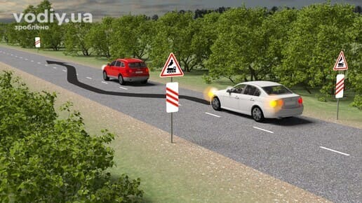 Білий та червоний автомобілі на дорозі, дорожні знаки 1.28, 1.31.2, 1.31.5, обгін перед залізничним переїздом поза населеним пунктом.