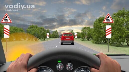 Дорожні знаки: 1.28 «Залізничний переїзд без шлагбаума», 1.31.1, 1.31.4 «Наближення до залізничного переїзду», червоний автомобіль попереду на дорозі.