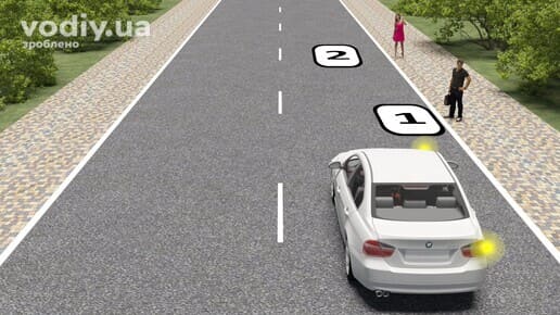 Білий автомобіль з увімкненим правим покажчиком повороту на дорозі, вибір місця для зупинки біля краю проїзної частини.