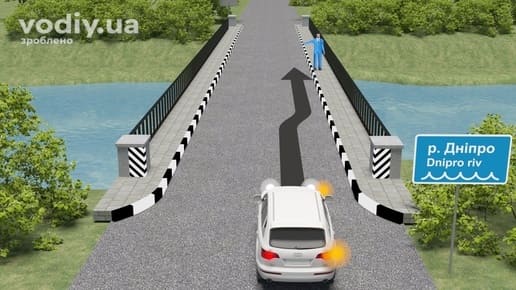 Білий автомобіль з увімкненим правим покажчиком повороту на в'їзді на міст через річку, зупинка на мосту.