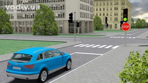 Блакитний автомобіль перед регульованим перехрестям, зелений сигнал світлофора, дорожній знак 2.2 «Проїзд без зупинки заборонено», розмітка 1.12.