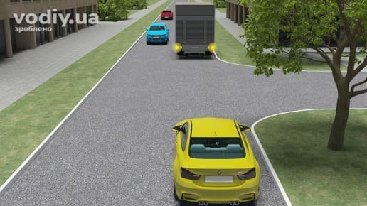 Жовтий автомобіль перед перехрестям, затор на дорозі, вантажівка з увімкненою аварійною сигналізацією та колона машин попереду.